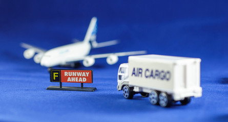 Air Cargo truck heading Runway Ahead sign and defocusing silhouette of an airplane - toy models