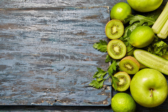 Collection of fresh green fruits and vegetables on a dark wooden background