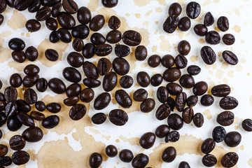 Coffee beans and coffee stains on a white tablecloth..