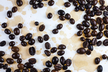 Coffee beans and coffee stains on a white tablecloth..