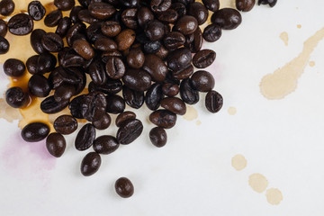 Coffee beans and coffee stains on a white tablecloth..