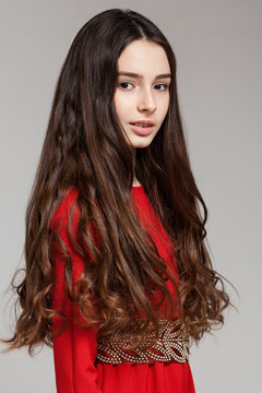 Portrait of a sensual brunette girl with long hair in a red dres