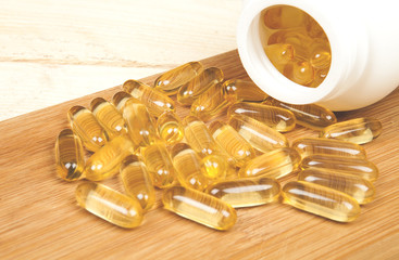 Cod liver oil omega 3 gel capsules isolated on wooden table background