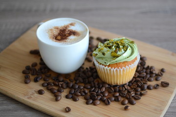 cup of cappuccino with cupcake on the wooden plate
