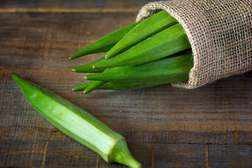 A heap of okra or Lady's fingers in a bag on wooden background