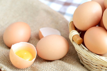 Wicker basket with eggs and raw egg on a linen tablecloth