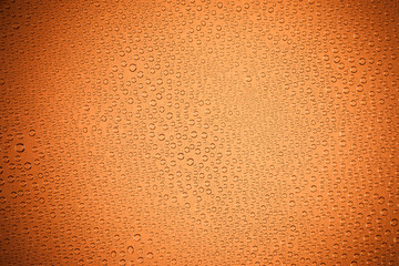 Orange background. background drops of water on clear glass..