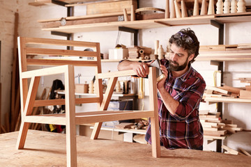 Furniture designer sanding a wooden chair frame