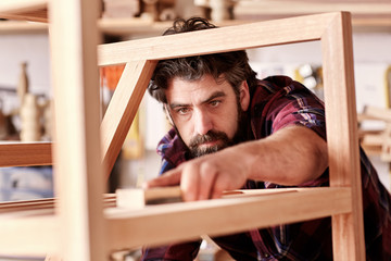 Craftsman sanding a wooden item in his woodwork studio