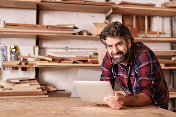 Smiling small business owner in woodwork studio with digital tab
