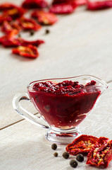 The tomato sauce in the saucepan, sun-dried tomatoes on wooden t