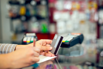 Woman holding credit card in hand, signing slip
