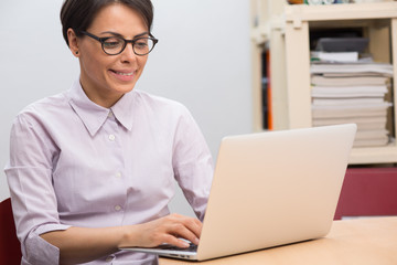 Attractive young woman with glasses using her laptop in an office