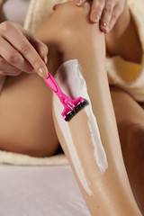 young woman shaving her legs with razor