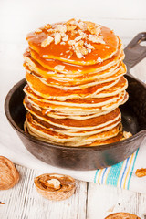 Pancakes with caramel and nuts on an old wooden background.
