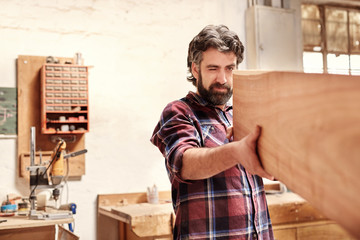 Skilled craftsman inspecting a wooden plank for quality of cut 