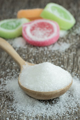 sugar in a wooden spoon on wooden background.