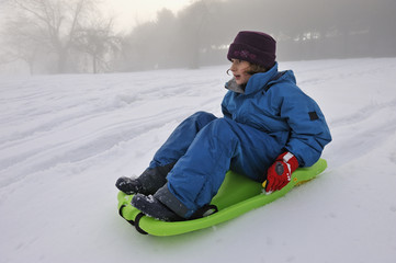 Fototapeta na wymiar Little girl sledging in a winter landscape
