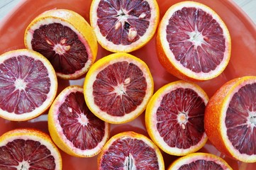 Plate of ruby red blood oranges cut in half on a red platter