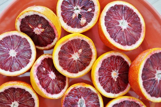 Plate of ruby red blood oranges cut in half on a red platter