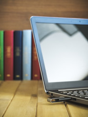 Neighbourhood concept of old and new. Laptop with USB flash drive. Several books on the background