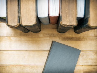 Closed book in front of several books on the table. Top view. Selective focus