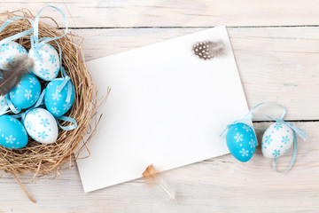 Easter background with blue and white eggs in nest and greeting