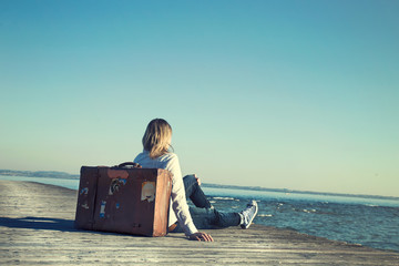 woman sitting on her suitcase waiting for the sunset in a specta
