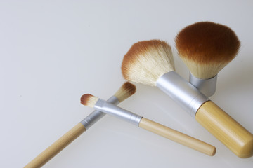 A set of bamboo brushes for applying makeup. Brushes for makeup: blush, eye shadow and correction. Of different sizes and diameters. Yellow and silver color on a white background.