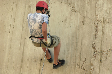 Young man practices rock climbing on a wall