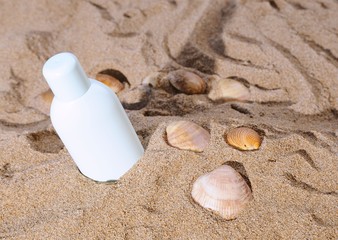 Sun lotion and several sea shells on sand