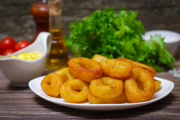 deep fried calamari with sauce and salad on a wooden background