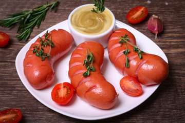 Pork sausages fried in a dish, sauce, tomato on the background of wooden boards