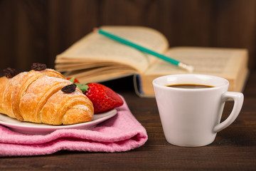 cup of coffee and a croissant and book