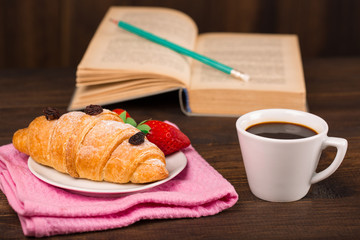 cup of coffee and a croissant and book