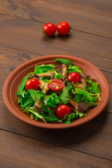 Fresh salad with chicken breast, arugula and tomato.