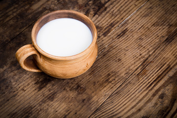 Milk in vintage cup on old wooden table