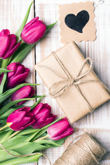 Obraz na płótnie Canvas Gift box and tulips bouquet on white wooden background - retro style