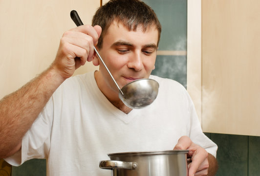 Young Man Tastes Food From  Saucepan