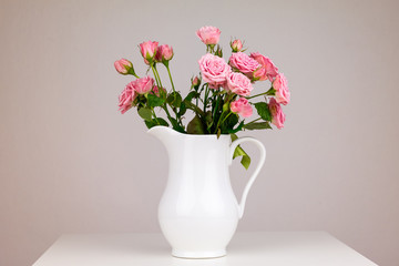 Fototapeta na wymiar Pink flowers in white jug. Roses in jug.