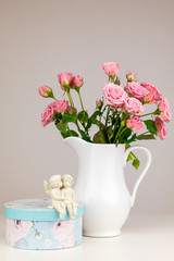 Pink flowers in white jug. Roses in jug. Two angels.