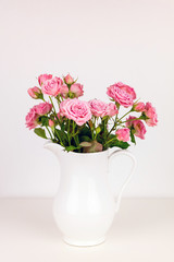 Obraz na płótnie Canvas Pink flowers in white jug. Roses in jug.