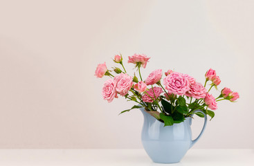 Pink flowers in blue jug. Roses in jug.