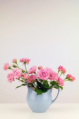 Obraz na płótnie Canvas Pink flowers in blue jug. Roses in jug.