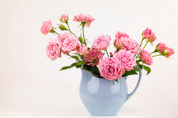 Pink flowers in blue jug. Roses in jug.
