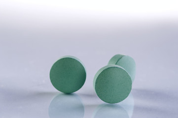 Green medicine pills on white background. Pharmaceutical medicament. Antibiotic, painkiller or narcotic, closeup.