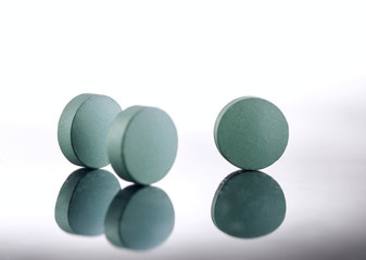 Green medicine pills on white background. Pharmaceutical medicament. Antibiotic, painkiller or narcotic, closeup.