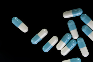Blue medical capsules on black background. Pharmaceutical medicament. Antibiotic, painkiller or narcotic, closeup.