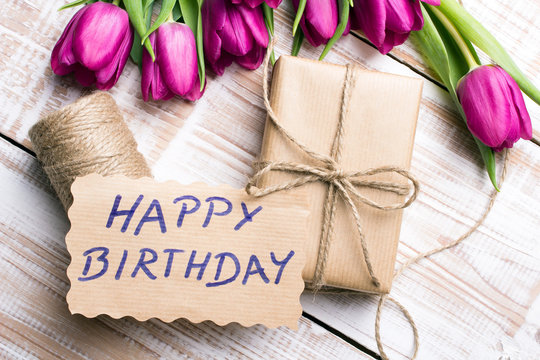 Birthday card and tulip bouquet on white wooden background