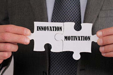 Business success concept. Connection between Innovation and Motovation, Businessman holding two pieces of a puzzle close up